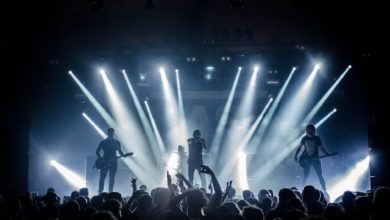 singer singing on stage beside guitar player and bass player