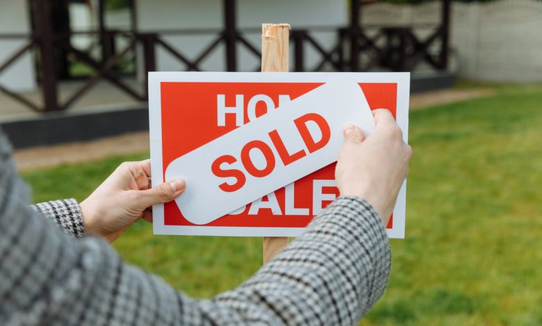 shallow focus photo of a realtor posting a sold sticker