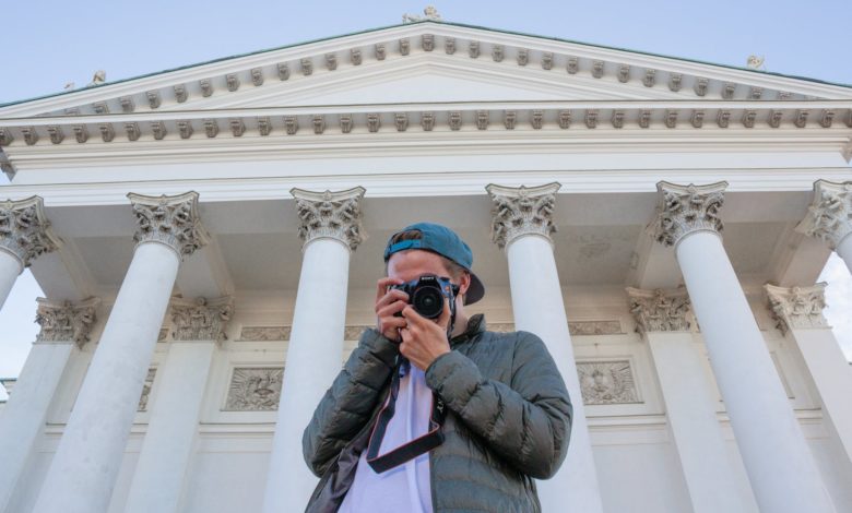 man holding camera beside white building outdoor