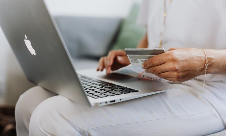 person using a macbook and holding a credit card