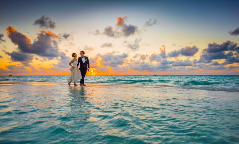 man and woman walking of body of water